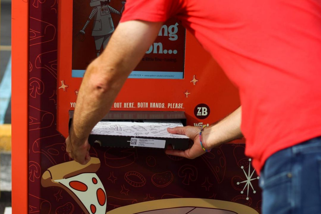 Man taking ZaBot Pizza box out of machine